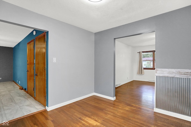 unfurnished room with wood-type flooring and a textured ceiling