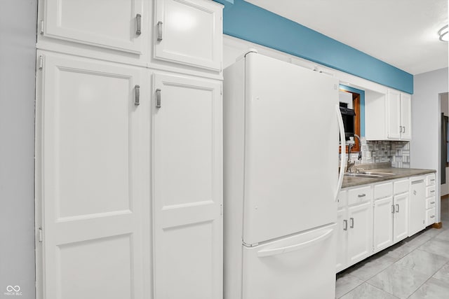 kitchen with backsplash, white cabinetry, white fridge, and sink