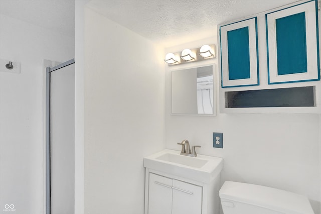 bathroom with a textured ceiling, an enclosed shower, vanity, and toilet