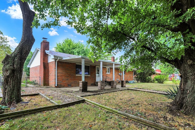 back of property with a lawn and a patio