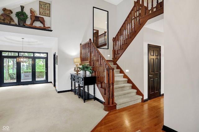 staircase with a high ceiling, a chandelier, and hardwood / wood-style flooring