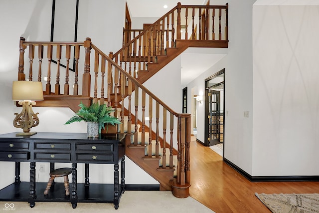 stairs with a towering ceiling and hardwood / wood-style floors