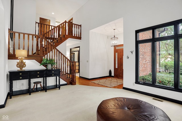 carpeted foyer with a notable chandelier and a high ceiling