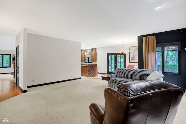 living room with an inviting chandelier, light colored carpet, and a healthy amount of sunlight