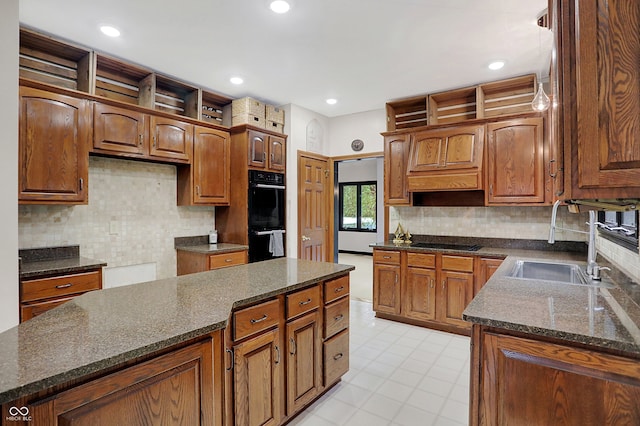 kitchen featuring dark stone counters, black appliances, decorative backsplash, and sink