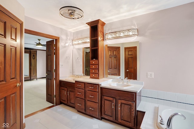 bathroom featuring a relaxing tiled tub, vanity, and tile patterned floors