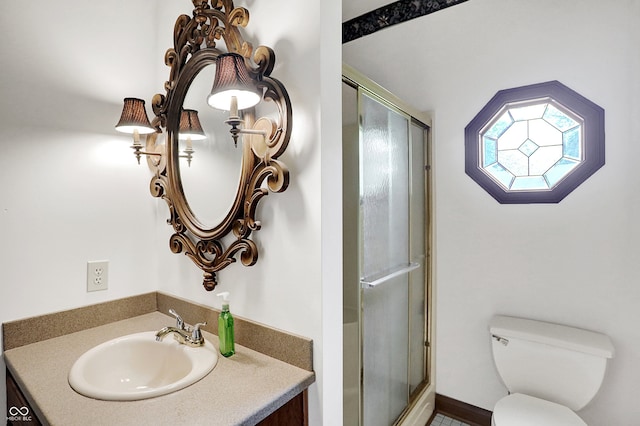 bathroom with vanity, a shower with shower door, and toilet