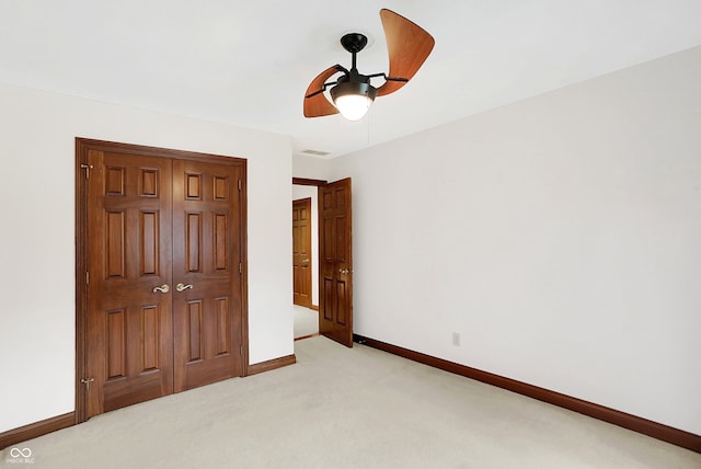 unfurnished bedroom with ceiling fan, light colored carpet, and a closet