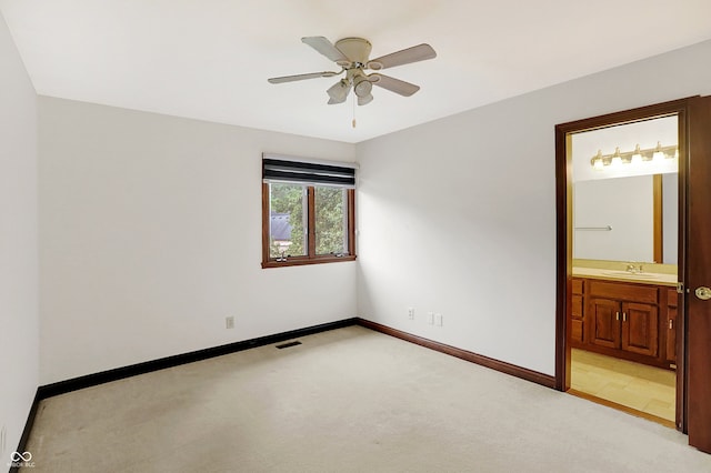 unfurnished bedroom with light colored carpet, sink, ceiling fan, and ensuite bathroom