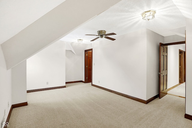 additional living space with light carpet, ceiling fan, and a textured ceiling