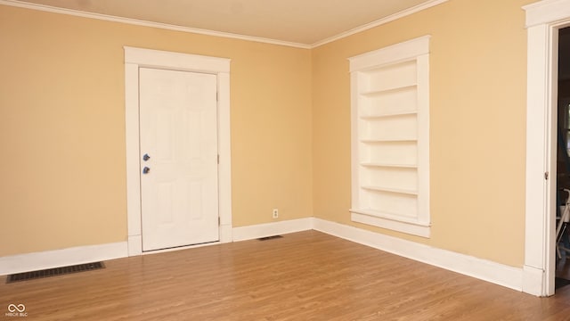 unfurnished room featuring hardwood / wood-style floors, ornamental molding, and built in features