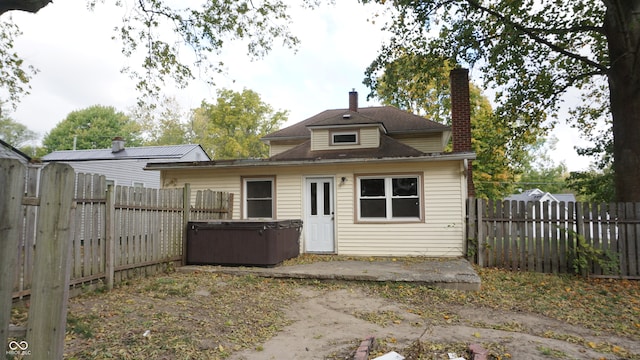 rear view of house featuring a hot tub and a patio