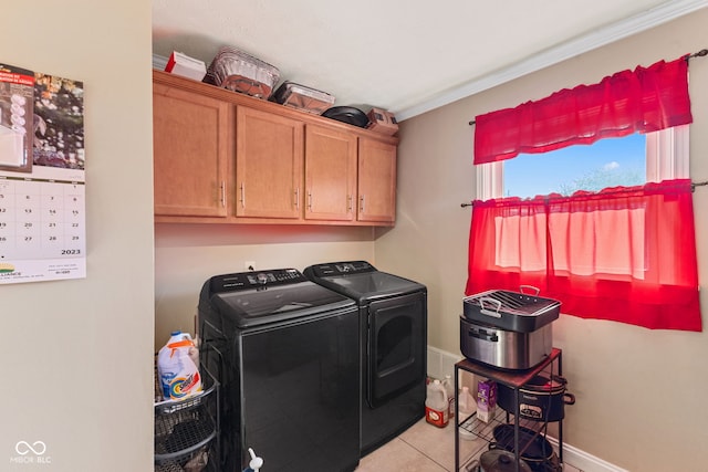 laundry room with ornamental molding, washer and dryer, cabinets, and light tile patterned floors