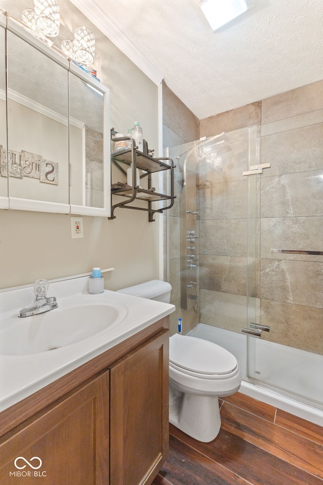 bathroom featuring a shower with door, wood-type flooring, toilet, vanity, and ornamental molding