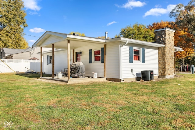 rear view of property with a yard, a patio, and central AC