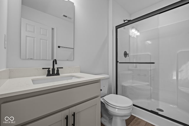 bathroom featuring vanity, an enclosed shower, hardwood / wood-style floors, and toilet