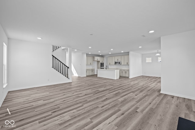 unfurnished living room featuring sink and light wood-type flooring