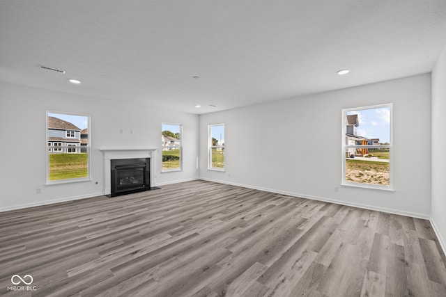 unfurnished living room featuring light wood-type flooring and a wealth of natural light