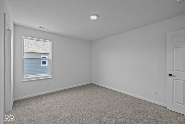 carpeted empty room featuring a textured ceiling