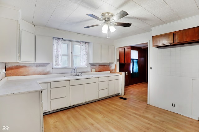 kitchen featuring light hardwood / wood-style floors, white cabinetry, tasteful backsplash, ceiling fan, and sink