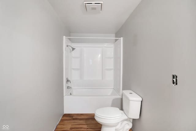 bathroom featuring hardwood / wood-style floors, toilet, and bathing tub / shower combination