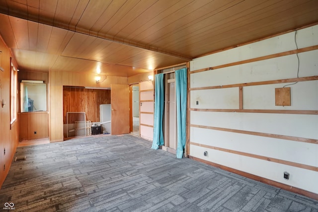 unfurnished living room featuring wooden ceiling, carpet, and wooden walls