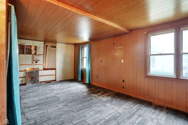 carpeted empty room with wooden ceiling and wooden walls