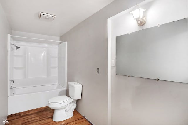 bathroom with tub / shower combination, hardwood / wood-style flooring, and toilet