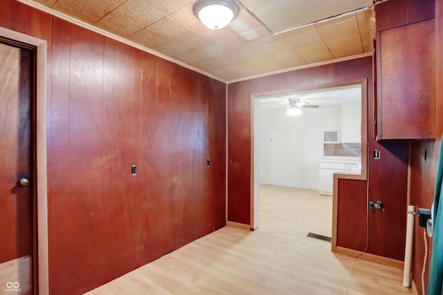 hallway featuring wood walls, crown molding, and light hardwood / wood-style floors