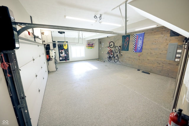 garage featuring wooden walls, electric panel, and a garage door opener