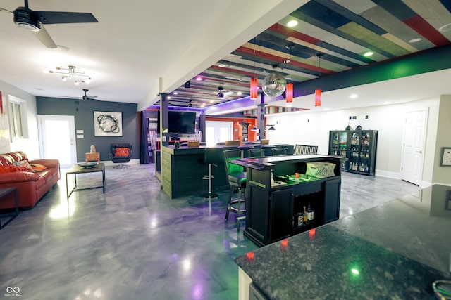 interior space featuring a kitchen island, a kitchen breakfast bar, concrete flooring, ceiling fan, and decorative light fixtures