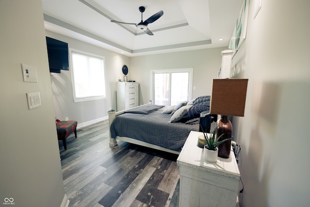 bedroom featuring dark wood-type flooring, a raised ceiling, and ceiling fan