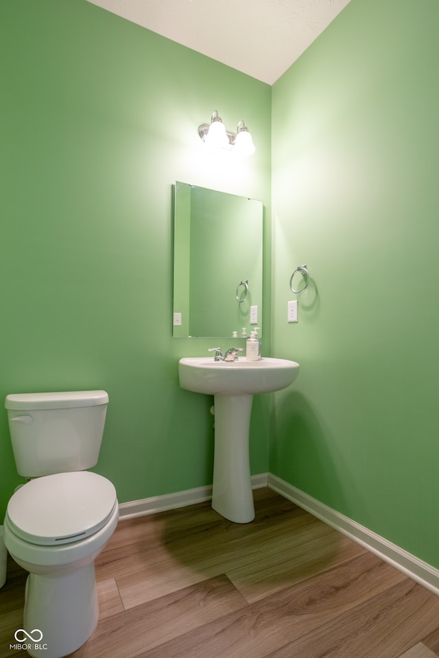 bathroom featuring wood-type flooring and toilet