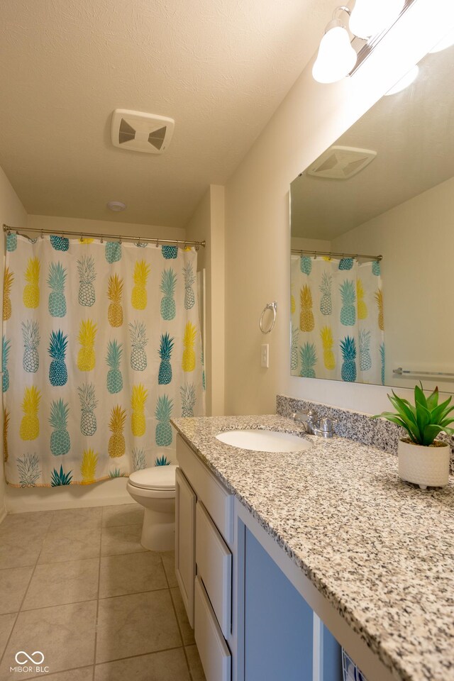 bathroom with a textured ceiling, vanity, toilet, and tile patterned floors