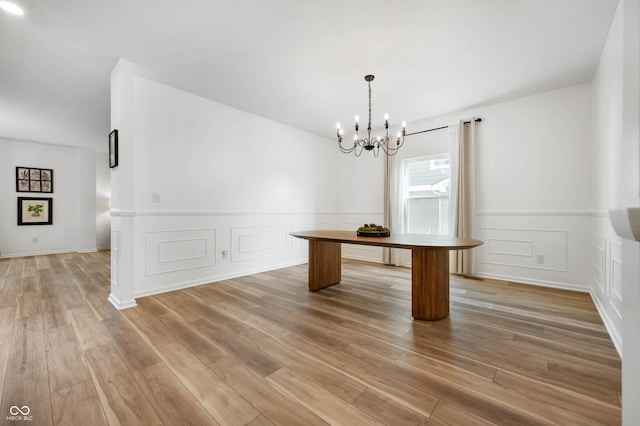 unfurnished dining area featuring wood-type flooring and a notable chandelier