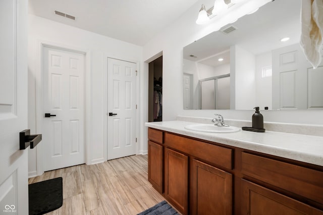 bathroom with vanity, hardwood / wood-style floors, and a shower with door