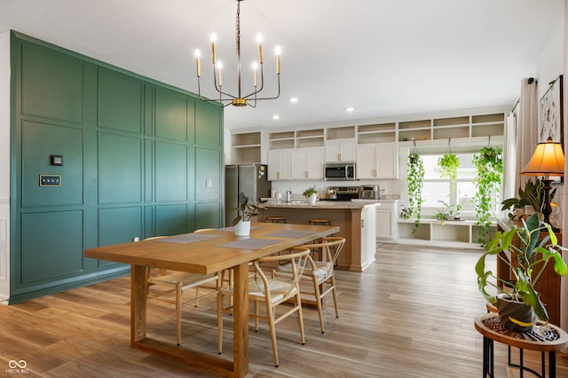 dining space featuring an inviting chandelier, light hardwood / wood-style flooring, and sink