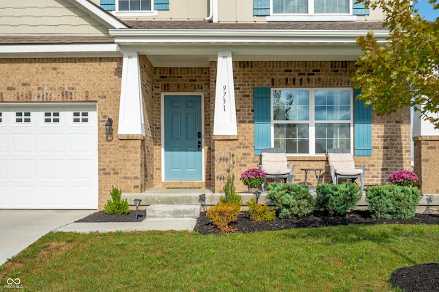 doorway to property featuring a garage, a yard, and covered porch