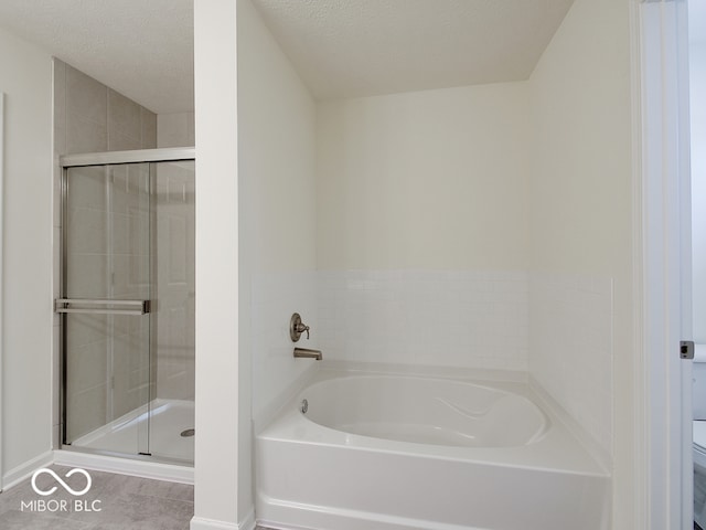 full bath with toilet, a shower stall, a textured ceiling, a bath, and tile patterned floors