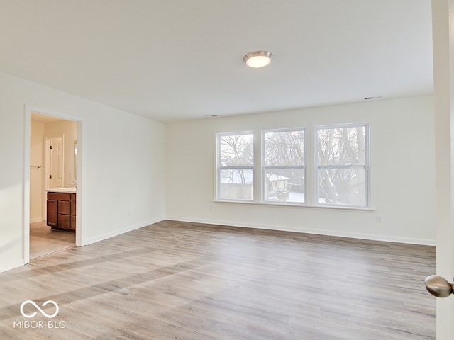 unfurnished room with light wood-style flooring and baseboards