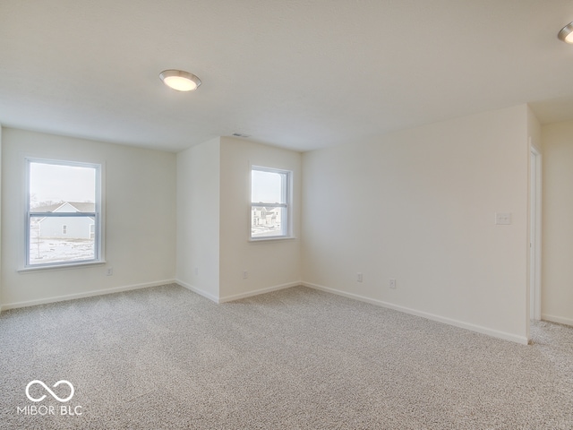 spare room featuring light carpet and baseboards