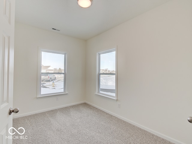 carpeted empty room featuring visible vents and baseboards