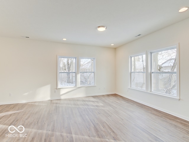 spare room featuring recessed lighting, a healthy amount of sunlight, visible vents, and light wood finished floors