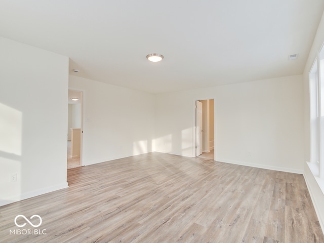 unfurnished room with light wood-type flooring, visible vents, and baseboards