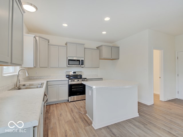 kitchen featuring light countertops, appliances with stainless steel finishes, a sink, and a center island