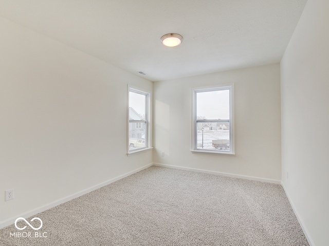 spare room with baseboards, carpet flooring, visible vents, and a healthy amount of sunlight