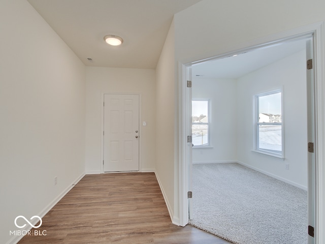 corridor featuring light wood finished floors and baseboards