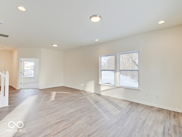 spare room featuring light wood finished floors, a wealth of natural light, and visible vents