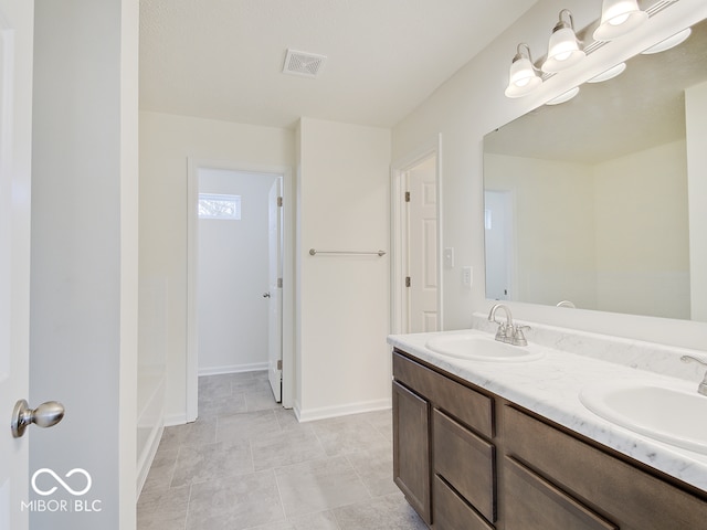 full bathroom with double vanity, a sink, visible vents, and baseboards