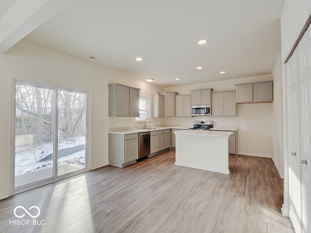 kitchen with gray cabinetry, stainless steel appliances, light countertops, and a center island